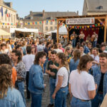 Une foule de personnes arborant des coupes mulet lors d'un festival en extérieur avec un groupe de musique sur scène.