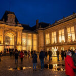 Palais des Beaux-Arts de Lille illuminé la nuit avec des visiteurs déambulant sur le parvis pavé lors de la nocturne.