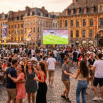 Une foule animée profite d'une soirée festive sur la Grand Place de Lille avec des gens qui dansent et un écran géant.