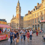 Foule animée à Lille lors de la célèbre Braderie, avec des stands de moules-frites et l'architecture historique en fond.