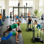 Groupe diversifié de personnes s'entraînant intensément dans une salle de sport lumineuse et moderne.